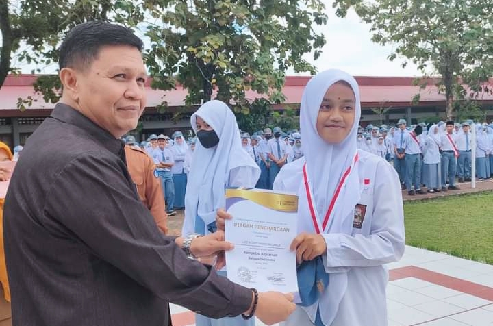 Ketua DPD Lembaga Pemberdayaan Masyarakat (LPM) Kota Padang Irwan Basir, Datuk Rajo Alam, SH.MM didampingi Kepala Sekolah SMAN 5 Padang menyerahkan Trofi dan penghargaan untuk siswa peraih medali Emas Olimpiade di bidang Bahasa Indonesia kepada Lupita Dwicahyani Salsabila.